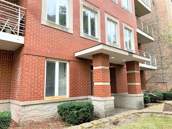 Front view of a multi-story brick building with balconies and large windows.