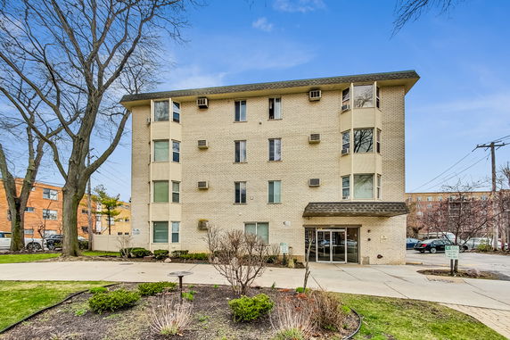 Front view of a multi-story apartment building with a brick facade and multiple windows.