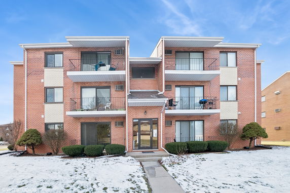 Front view of a multi-story brick apartment building with balconies.