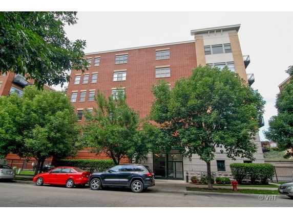 Front view of a multi-story brick building with parking in front.