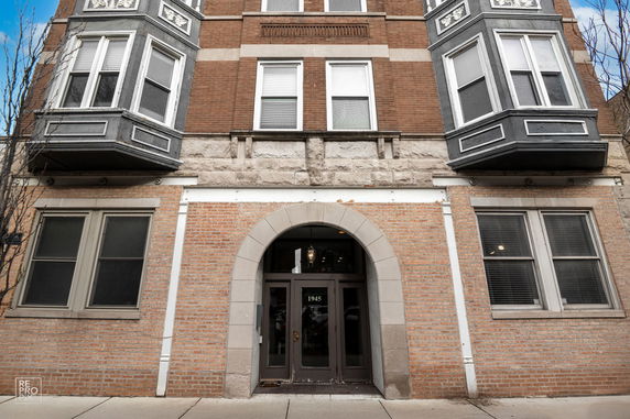 Front view of a multi-story brick building with large windows and an arched entrance.