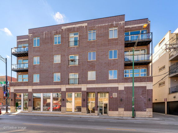 Front view of a multi-story brick building with balconies and large windows.