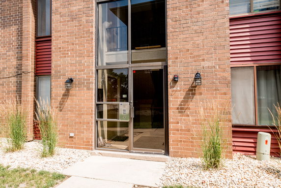 Front view of a brick apartment building with glass entrance doors.