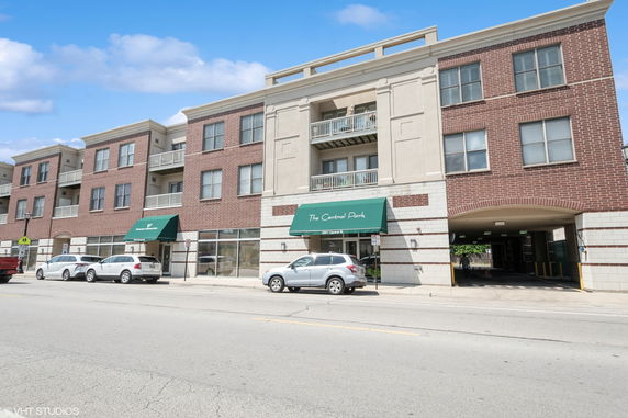 Front view of a multi-story apartment building with balconies and an entrance awning.