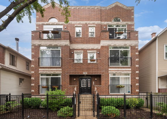 Front view of a multi-story brick building with balconies and large windows.