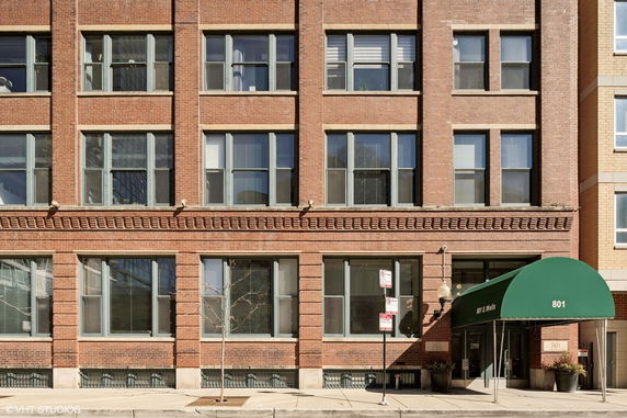 Front view of a multi-story brick building with large windows and a green awning over the entrance.