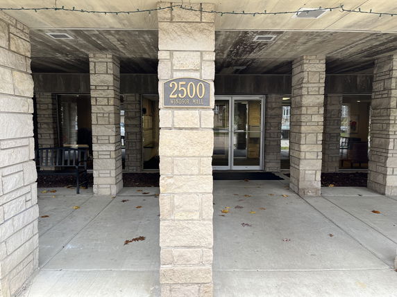 Front view of a building entrance with stone pillars and a double glass door.