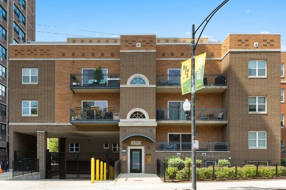 Front view of a three-story brick apartment building with balconies.