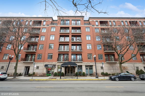Front view of a multi-story brick apartment building with balconies.