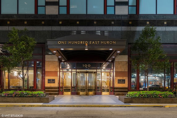 Front view of a building entrance with signage 'One Hundred East Huron'.