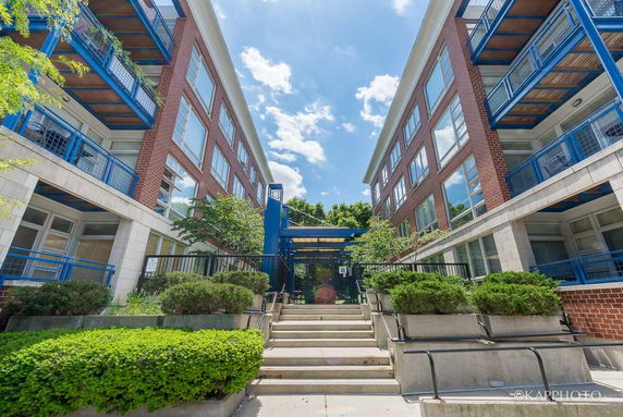 Front view of a multi-story building with blue railings and glass windows.