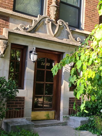 Front view of a building entrance with decorative stonework around the door.