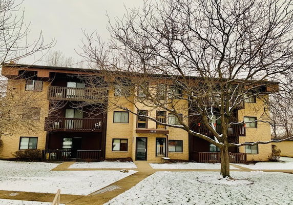 Front view of a three-story apartment building with covered balconies and a central entrance.