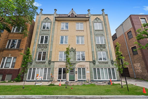 Front view of a four-story residential building with ornate architectural details.