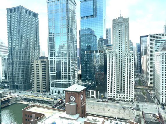 Panoramic view of skyscrapers in a city skyline with a river and streets below.
