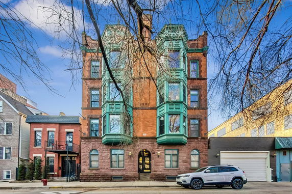 Front view of a multi-story brick building with large bay windows.