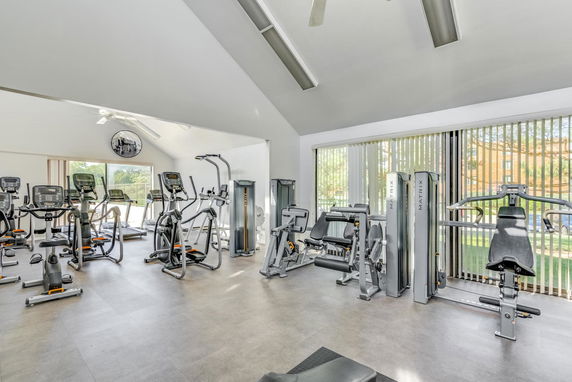 Indoor gym area with exercise equipment including treadmills, elliptical machines, and weight machines.