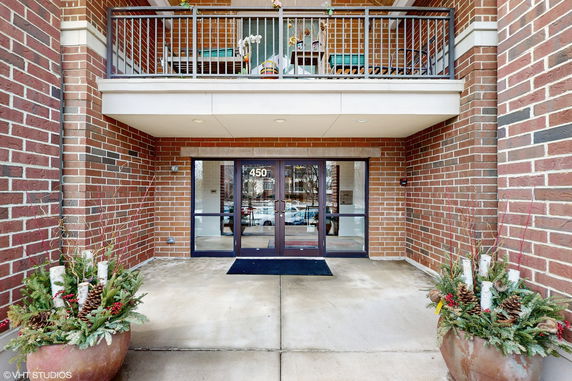 Front view of a building entrance with a balcony and brick façade.