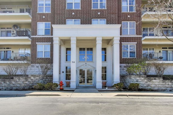 Front view of a multi-story brick building with balconies and white columns at the entrance.