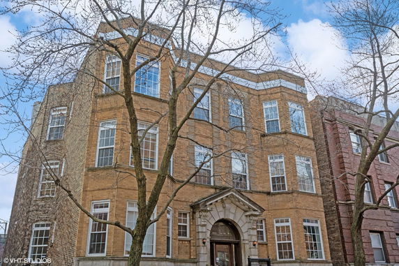 Front view of a multi-story brick building with large windows.