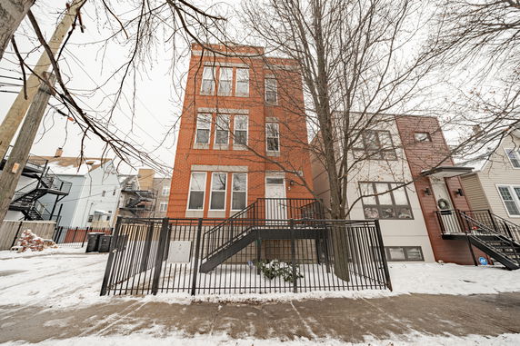 Front view of a multi-story brick building with stairs and metal railings.