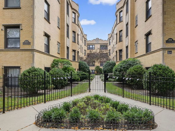 Front view of a multi-story brick apartment building with gated entrance.