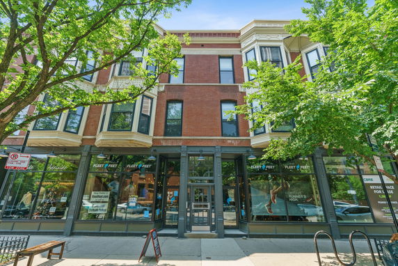 Front view of a multi-story building with retail spaces on the ground floor.