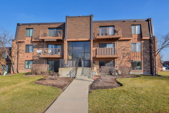Front view of a three-story brick apartment building with balconies.