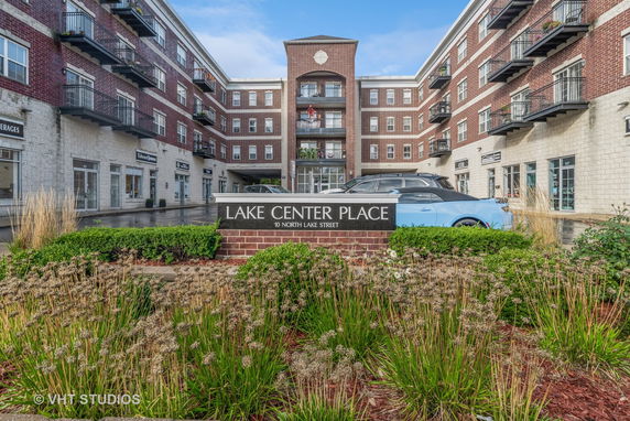 Front view of a multi-story building named Lake Center Place with multiple balconies and commercial spaces on the ground floor.
