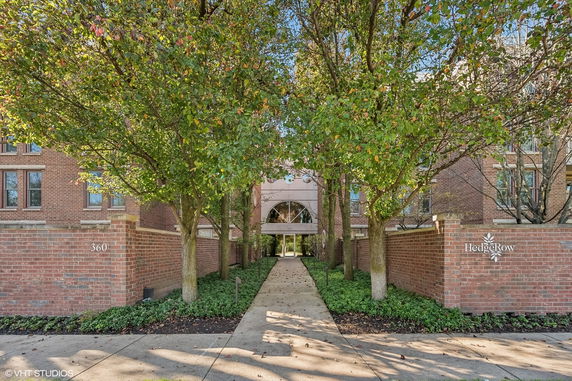 Front view of a brick building entrance with trees and a walkway.