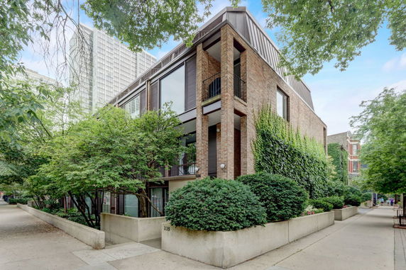 Front view of a multi-story brick building with large windows and greenery.