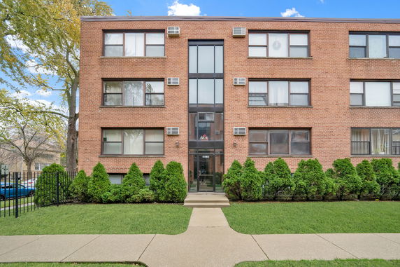 Front view of a brick three-story building with multiple windows and entrance.