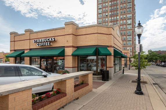 Front view of a Starbucks coffee shop building with brick exterior and green awnings.