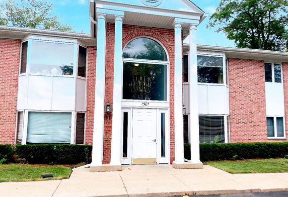 Front view of a two-story brick building with large white columns and a central glass entrance.