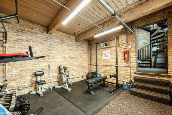 Indoor gym area with weightlifting equipment and a spiral staircase.