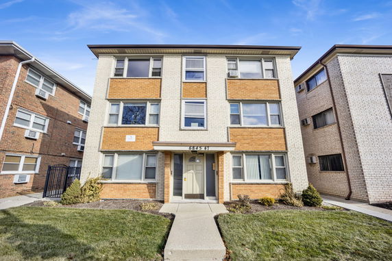 Front view of a three-story apartment building with brick facade.