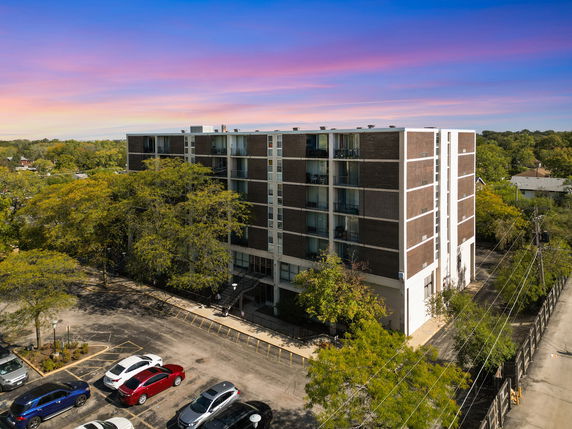 Front view of a multi-story apartment building with a parking area.