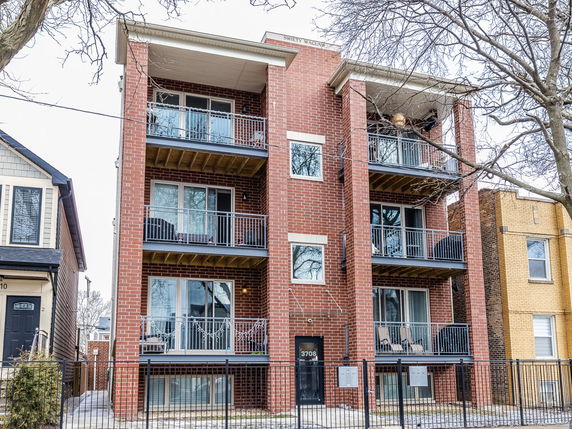 Front view of a multi-story brick apartment building with balconies.