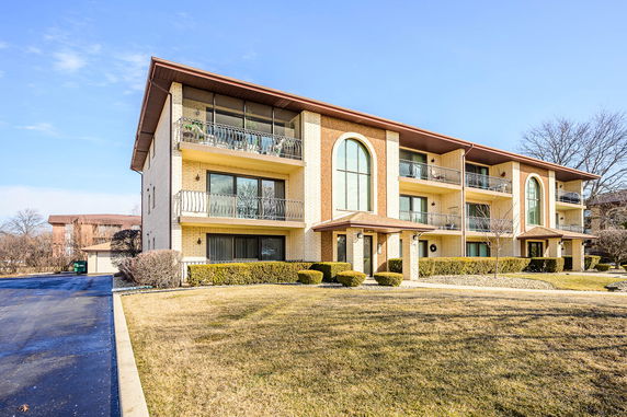Front view of a three-story apartment building with balconies and large windows.