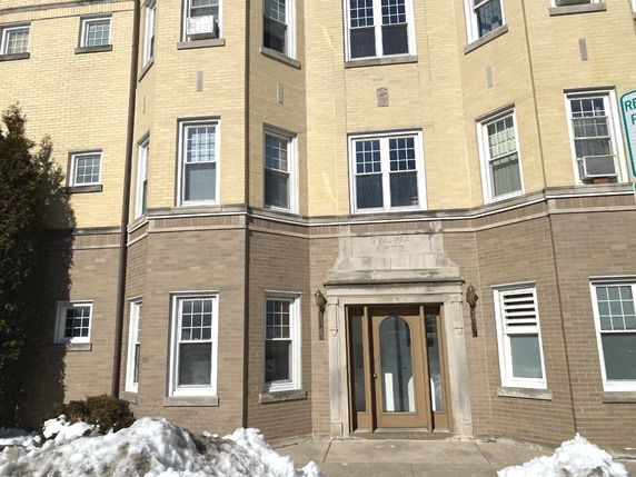 Front view of a multi-story apartment building with brick exterior and multiple windows.