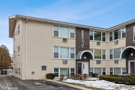 Front view of a three-story apartment building with cream and brown brick exterior.