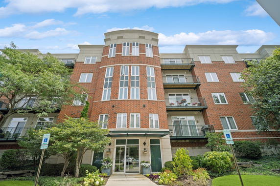 Front view of a multi-story brick apartment building with balconies.