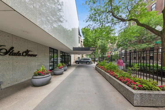 Front view of a multi-story building entrance with canopy and planters.