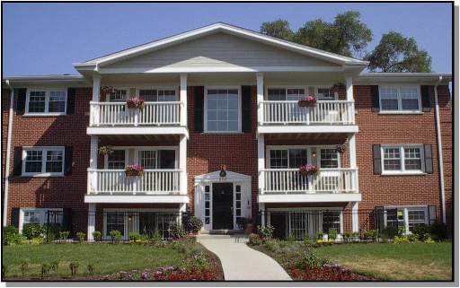 Front view of a three-story brick apartment building with balconies.