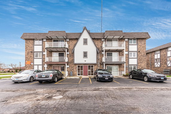 Front view of a three-story apartment building with brick facade and balconies.