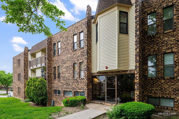 Front view of a multi-story brick apartment building with balconies.