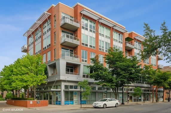 Front view of a modern multi-story building with large windows and balconies.