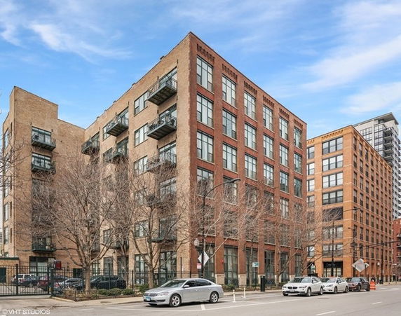 Front view of a multi-story brick building with large windows and small balconies.