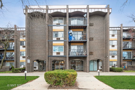Front view of a multi-story brick apartment building with balconies.
