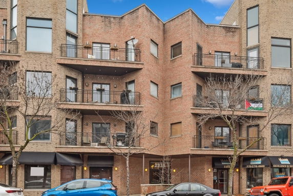 Front view of a multi-story brick apartment building with balconies.